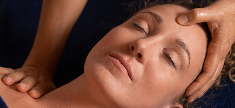 Jeune femme au visage apaisé, savourant un massage équilibrant le corps et l'esprit